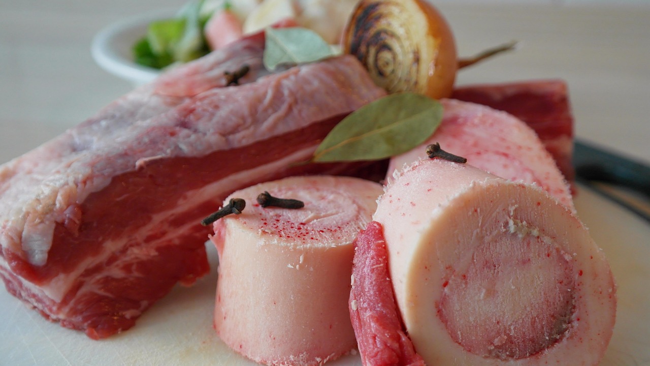 Bottiglia di brodo di carne con ingredienti freschi su un tavolo di legno, ricetta tradizionale della nonna.